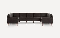 a black leather sectional sofa with wooden legs and arm rests on an isolated white background