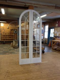 an empty room with wooden floors and white arched glass doors in the center, surrounded by other woodworking tools