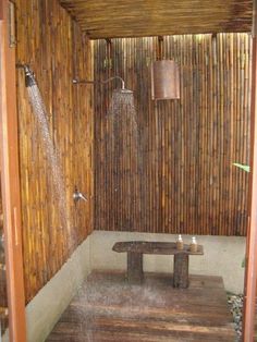 an outdoor shower with water coming from the faucet and wooden bench in front of it