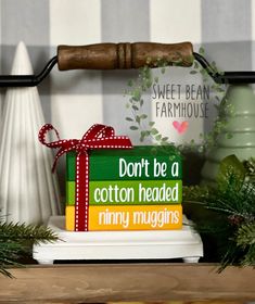 a stack of books sitting on top of a wooden shelf next to a christmas tree