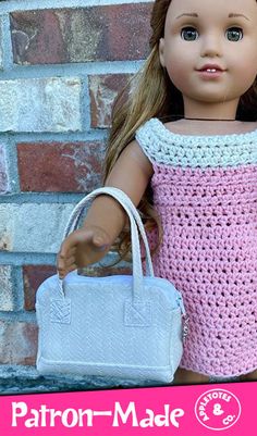 a doll holding a white purse next to a brick wall