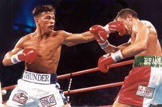 two men are boxing in the ring, one is hitting the other with his gloves