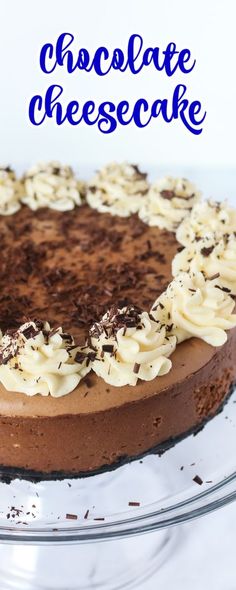 a chocolate cheesecake with white frosting and sprinkles on a glass platter