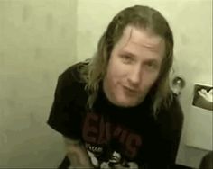 a man with long hair sitting in front of a toilet