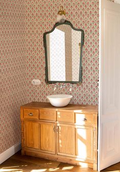 a bathroom sink sitting under a mirror on top of a wooden cabinet next to a doorway