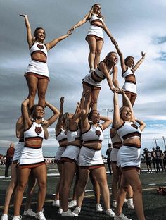 a group of cheerleaders are doing tricks on the field with their hands in the air