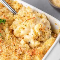 a white casserole dish filled with macaroni and cheese, garnished with parsley