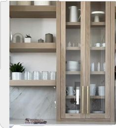 a kitchen with wooden cabinets and white dishes on the counter top, along with glass doors