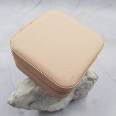 a tan leather case sitting on top of a rock next to a white marble slab