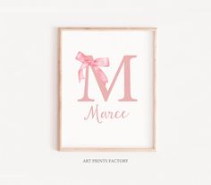 a pink print with the letter m and a bow on it's head, in front of a white wall