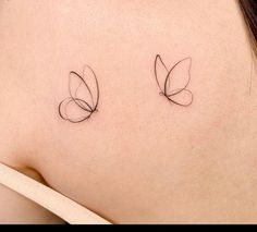 two small tattoos on the back of a woman's shoulder