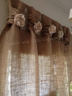 curtains with flowers on them hanging from the side of a window sill in front of a lamp