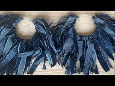 two pieces of blue fabric with fringes on top of a wooden table next to each other