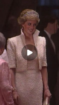 a woman in a white dress and tiara standing next to an older man wearing a pink suit