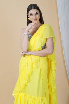 Groove at the cocktail party or a friend's wedding in this stunning frilly saree. Whimsical and lightweight, it is well paired with a contrasting strappy silver blouse that enhances the overall appeal to make it a perfect pick this season.Style Frill saree Silver embellished blouse Sunshine yellow hue Georgette fabric Specifications Model height - 5'9" Model wearing - S Bollywood Style Ruffled Saree For Evening, Elegant Summer Lehenga With Traditional Drape, Elegant Pre-draped Saree With Ruffles For Navratri, Glamorous Pre-draped Saree For Navratri, Summer Party Georgette Sets, Festive Evening Saree With Ruffles, Elegant Ruffled Blouse Piece For Festivals, Elegant Festival Blouse Piece With Ruffles, Elegant Summer Pre-draped Saree With Dupatta