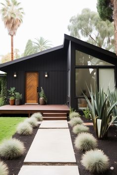 a black house with plants in the front yard and steps leading up to the entrance