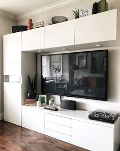 a flat screen tv sitting on top of a white entertainment center in a living room