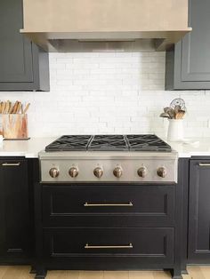 a stove top oven sitting inside of a kitchen next to black cabinets and counter tops