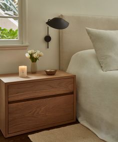 a bedroom with a bed, night stand and flowers on the nightstand next to it