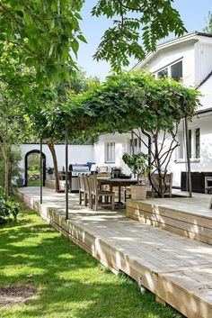 an outdoor dining area with wooden steps leading up to the house