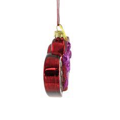 a red glass ornament hanging from a string on a white background with a purple ribbon