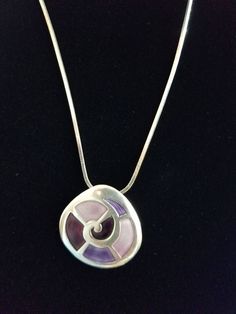 Sterling silver necklace with swirly silver pendant with purple inlay. Purple inlay is in various shades of purple. Purple Sterling Silver Necklace With Large Pendant, Purple Necklace With Large Round Pendant, Nickel Free Purple Metal Necklace, Nickel-free Purple Metal Necklace, Purple Metal Pendant Necklaces, Nickel Free Purple Sterling Silver Necklace, Nickel-free Purple Sterling Silver Necklace, Purple Pendant Necklace With Large Pendant, Purple Necklace With Large Pendant