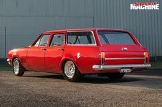 an old red station wagon parked in front of a building