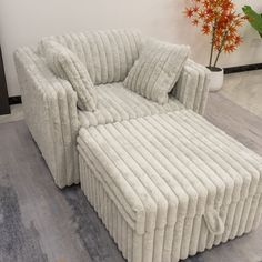 a large white couch sitting on top of a wooden floor next to a vase with flowers