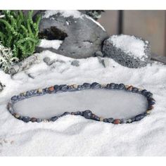 a stone circle in the snow next to some rocks and plants with beads around it