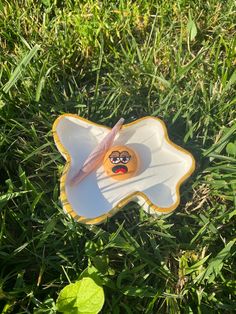 a frisbee with a smiley face on it laying in the grass next to a toothbrush