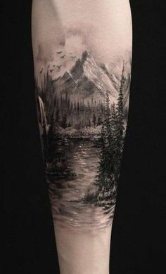 a man's leg with a landscape tattoo on it