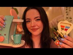 a woman holding up a toy kitchen set and coffee cup in front of her face