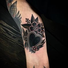 a tattoo with a heart and flowers on the arm that has an arrow in it