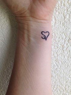 a small tattoo on the wrist of a person with a heart and two letters in it