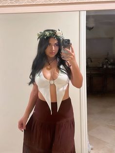 a woman taking a selfie in front of a mirror wearing a skirt and crop top