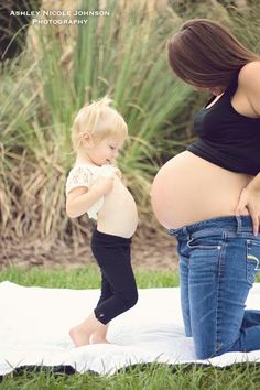 a pregnant woman standing next to a child