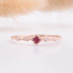 a close up view of a ring with a red stone in the middle and white diamonds on it