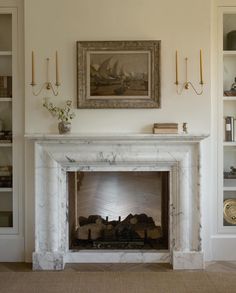 a fireplace in a living room next to a book shelf and painting on the wall