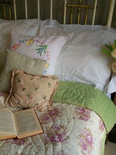 an open book sitting on top of a bed next to pillows