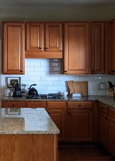 a kitchen with wooden cabinets and marble counter tops