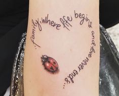 a ladybug tattoo on the arm with words written in cursive writing