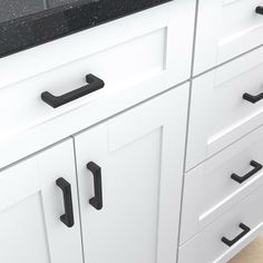 a kitchen with white cabinets and black counter tops