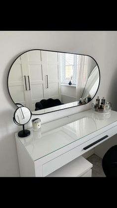 a white desk with a large mirror on it's side and a black chair next to it