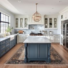 a large kitchen with white cabinets and blue island