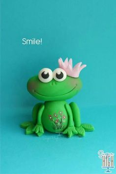 a green frog with a pink flower on its head and the words smile written above it