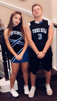 a man and woman standing next to each other in front of a stair case with their hands on their hips