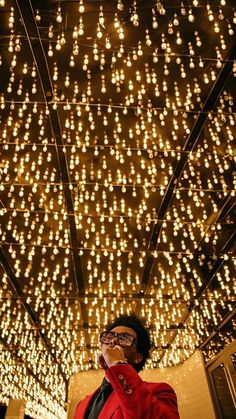 a man in a red suit is talking on his cell phone while standing under a string of lights