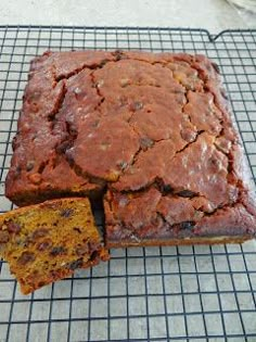 a loaf of bread sitting on top of a cooling rack next to a piece of cake