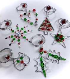 a collection of christmas ornaments are arranged on a white surface with red, green and silver beads