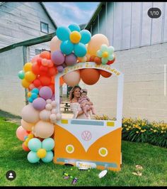 a woman and child are sitting in a vw bus decorated with balloons